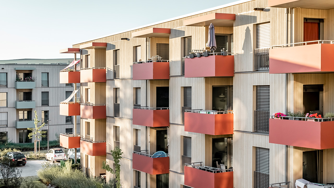 Wohngebäude aus Holz im Schildacker mit roten Balkonen