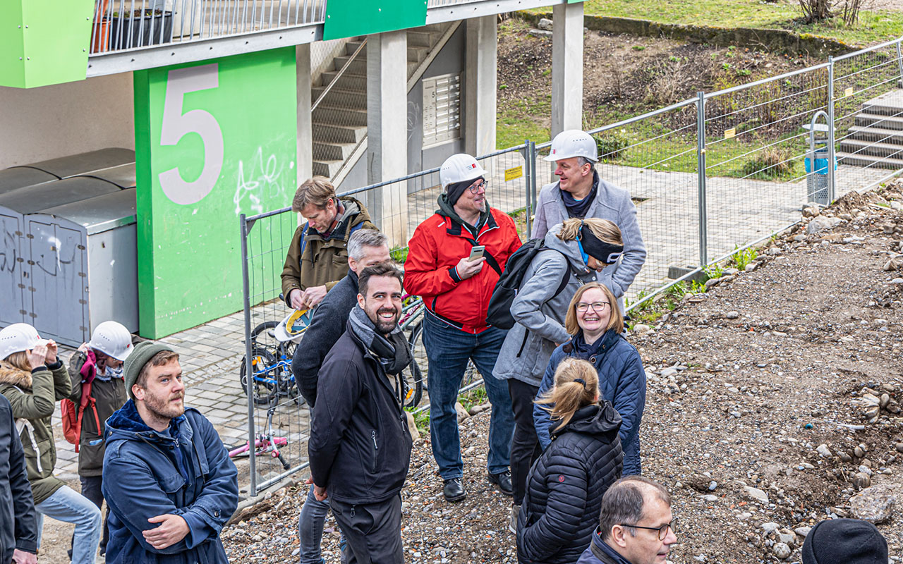 Menschen schauen bei der Montierung der Holzmodule an der Bergäckerstraße zu